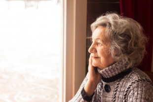 Una mujer mayor mirando por la ventana