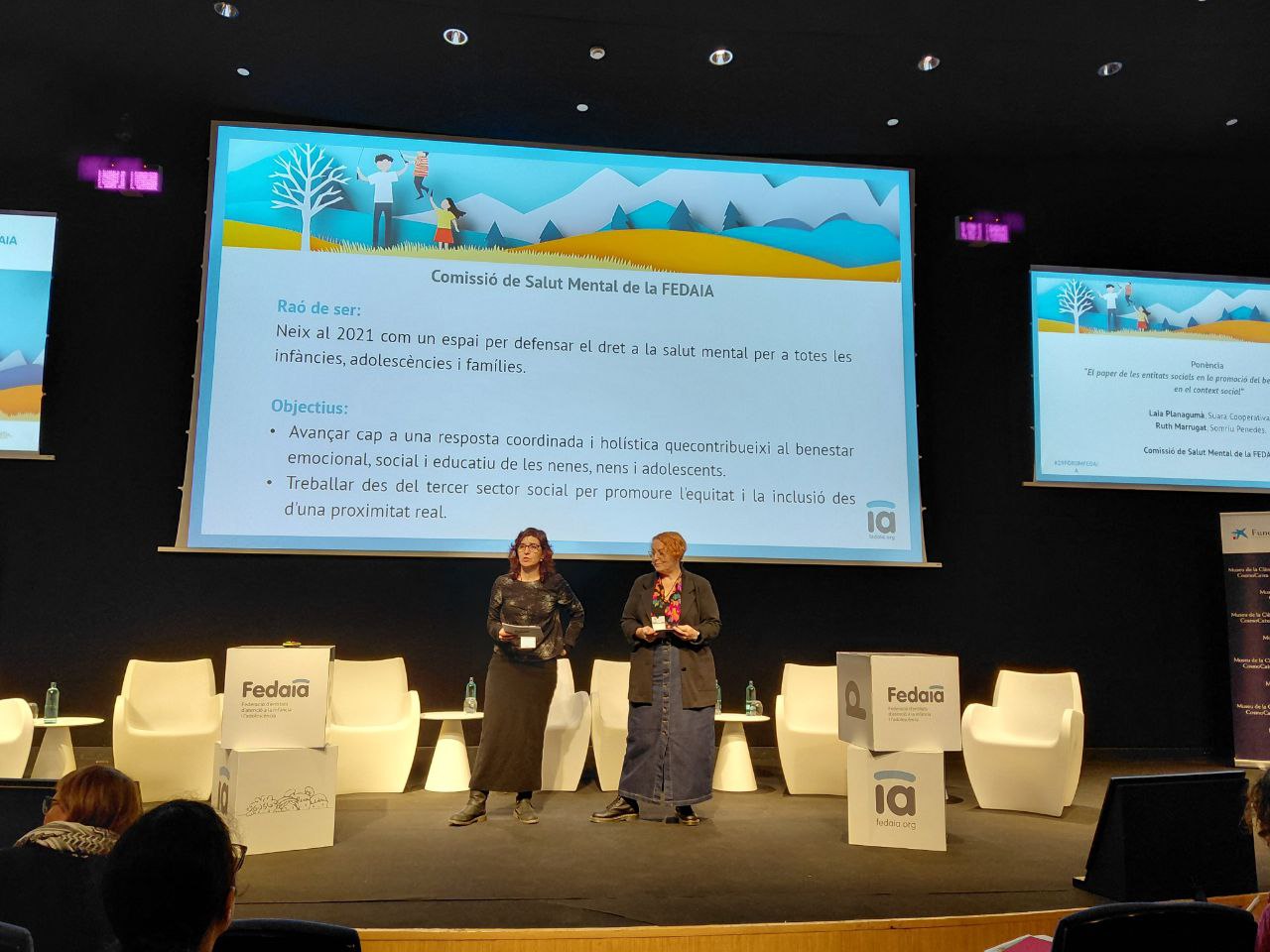 dues eprsones a l'escenari durant la ponencia central del fòrum fefaia