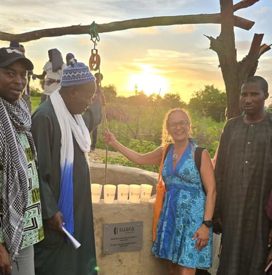 Pepi Ruiz, persona de Suara Cooperativa que liderat aquest projecte de transformació de l'entorn, amb els caps de la comunitat local el dia de la inauguració del pou