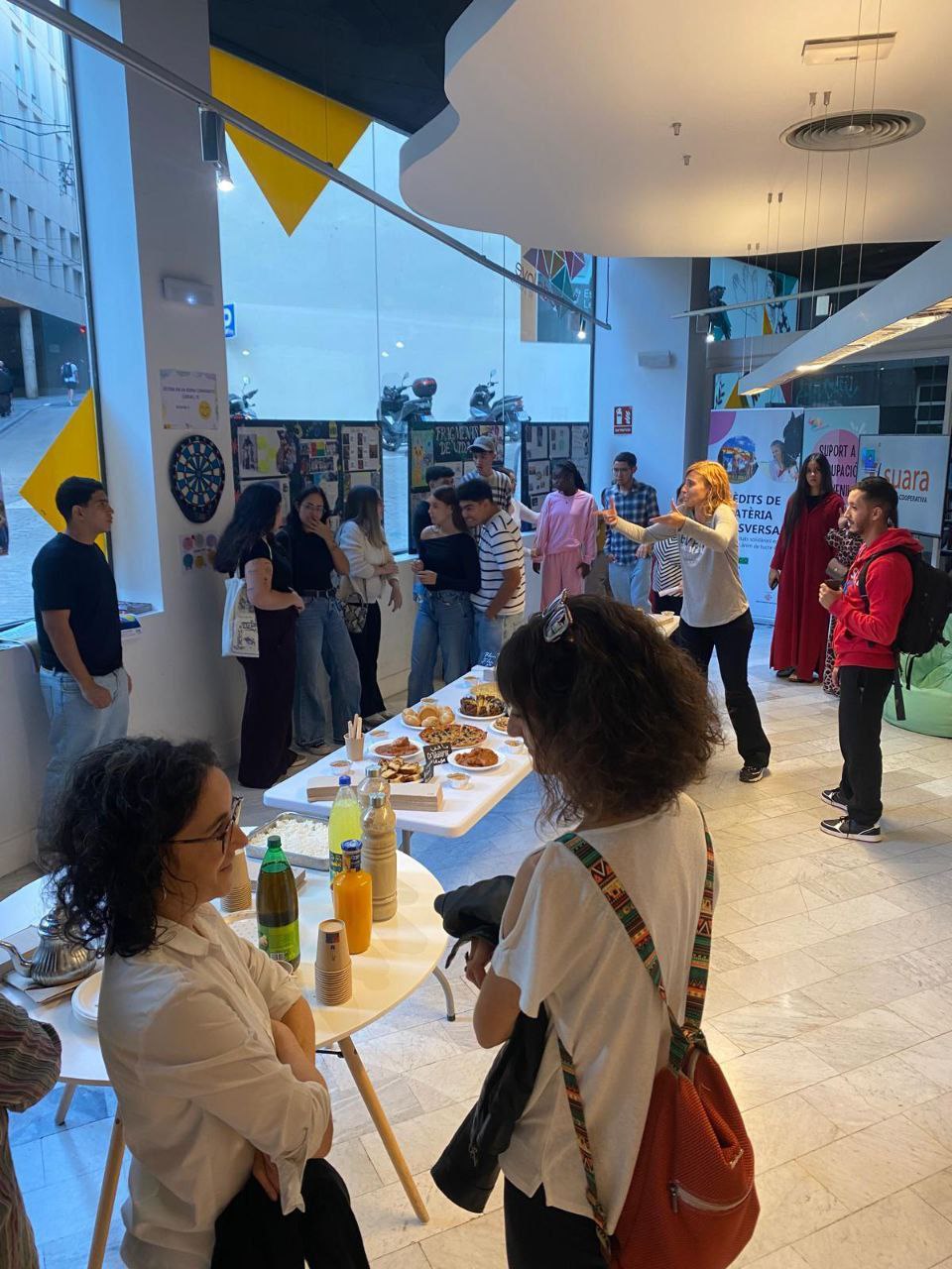 personas reunides en una presentaciço al voltan d0una taula amb menjar