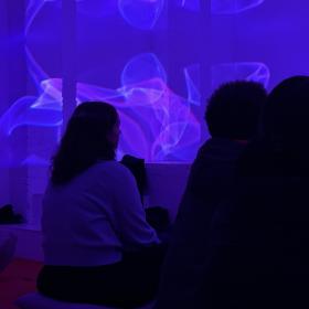 sala immersiva proyección azul con 3 personas jóvenes sentadas 
