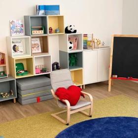 espai barnahus: sala amb prestageries, contes joguines, una pizzara al cantó dret, i una butaca i catifa al centre