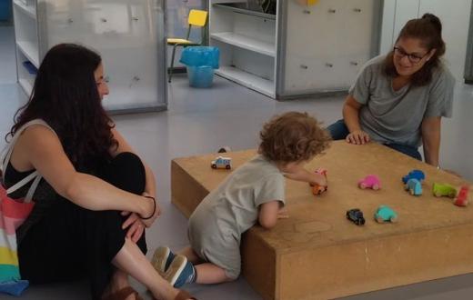 educadora i família jugant amb un infant els primers dies d'escola