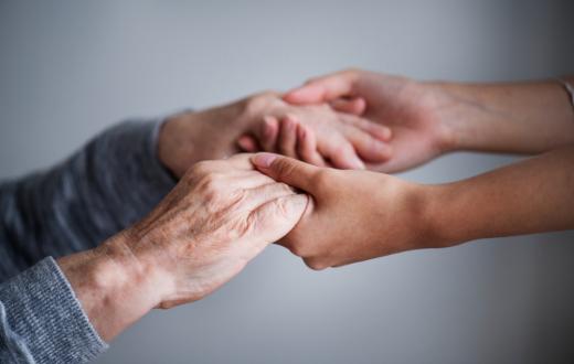 Unes mans de dona jova agafen amb cura les mans d'una dona gran