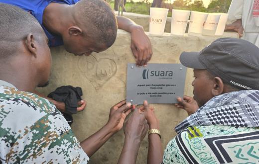 Tres homes pengen la placa de Suara Cooperativa en el pou que s'ha construït al Senegal