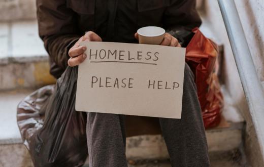 Un home aguanta un cartell. en el qual demana ajuda, perquè viu al carrer 