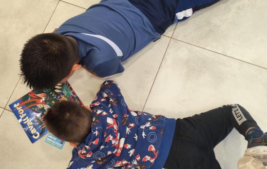 Dos nens del CA de Terres de l'Ebre estan estirats junts a terra llegint Cavall Fort