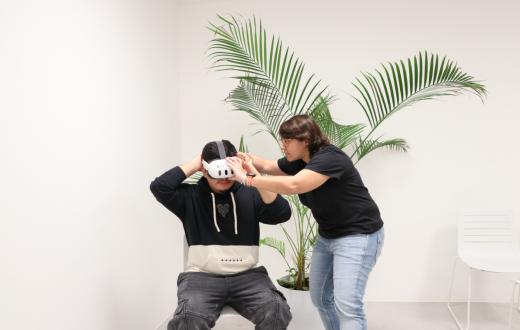La responsable de realitat virtual, Natalia Alonso, posa les ulleres a un jove per treballar una experiència de realitat virtual