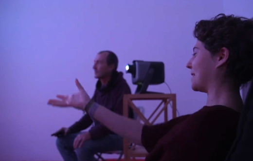 una noia senyalant a la mà i explicant la seva experiència al seu terapeuta en una sala de realitat immersiva