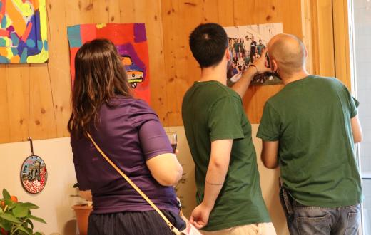Persones treballadores mirant una de les fotos de l'exposició sorgida arran de la residència artística