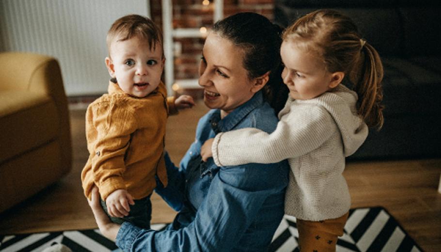 una dona abraçant a dos infants