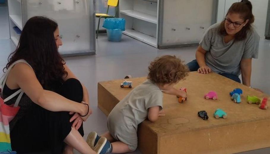 educadora i família jugant amb un infant els primers dies d'escola