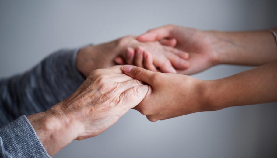 Unes mans de dona jova agafen amb cura les mans d'una dona gran