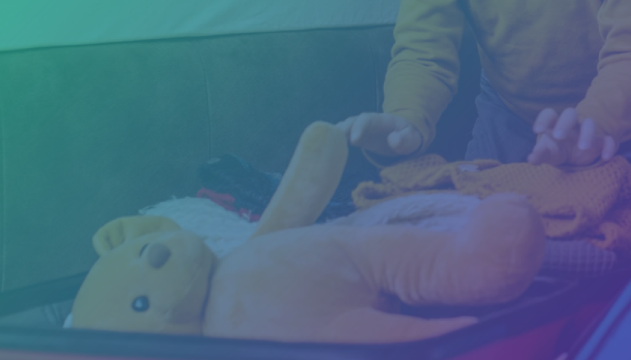 Photo of a child putting a yellow teddy bear in a suitcase