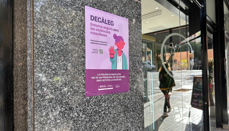 Un cartell de la campanya per difondre el "Decàleg: entorns segurs contra la violència masclista" llueix a l'entrada d'un establiment comercial