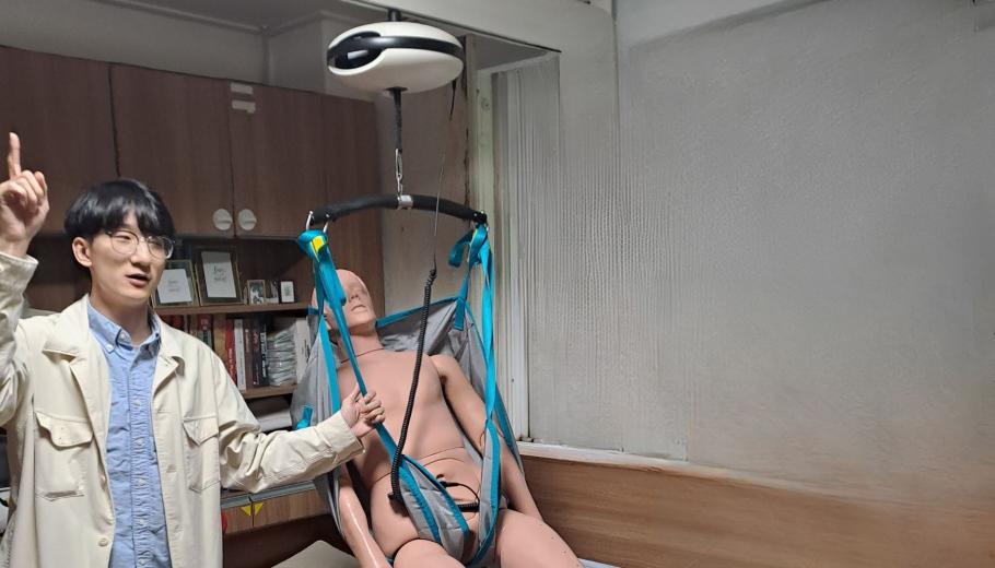 A Korean person showing a robot designed to lift a person in a bed.