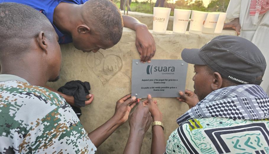 Tres homes pengen la placa de Suara Cooperativa en el pou que s'ha construït al Senegal