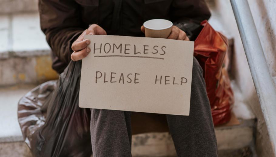 Un home aguanta un cartell. en el qual demana ajuda, perquè viu al carrer 
