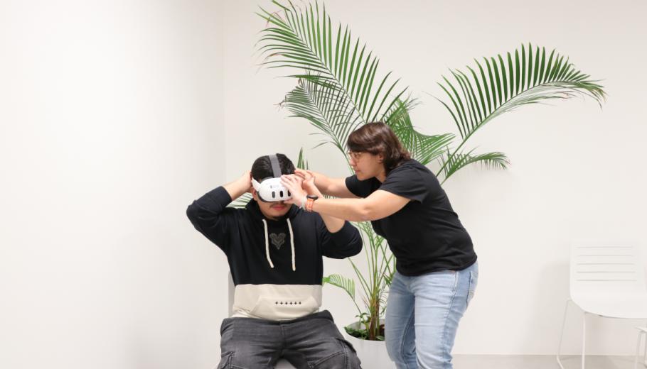 La responsable de realitat virtual, Natalia Alonso, posa les ulleres a un jove per treballar una experiència de realitat virtual