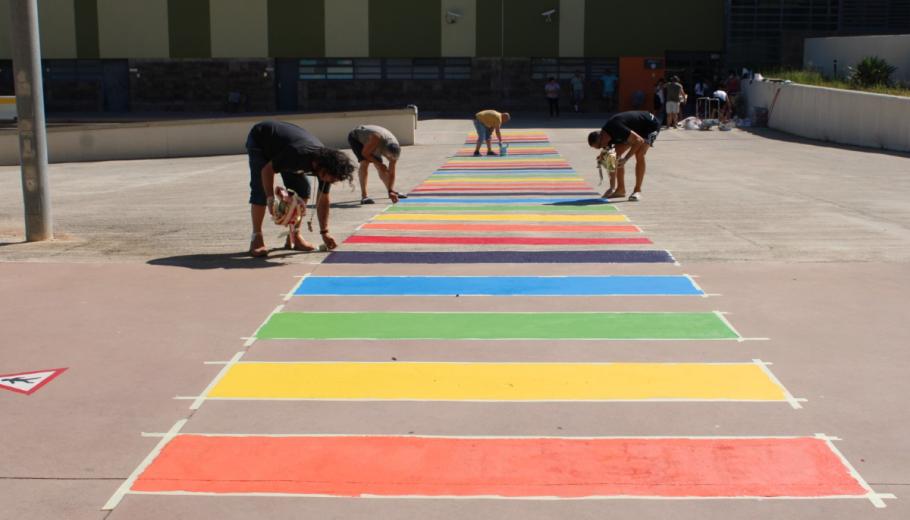 Un grup de persones pinten el pas de zebra amb els colors de la bandera LGTBIQ+