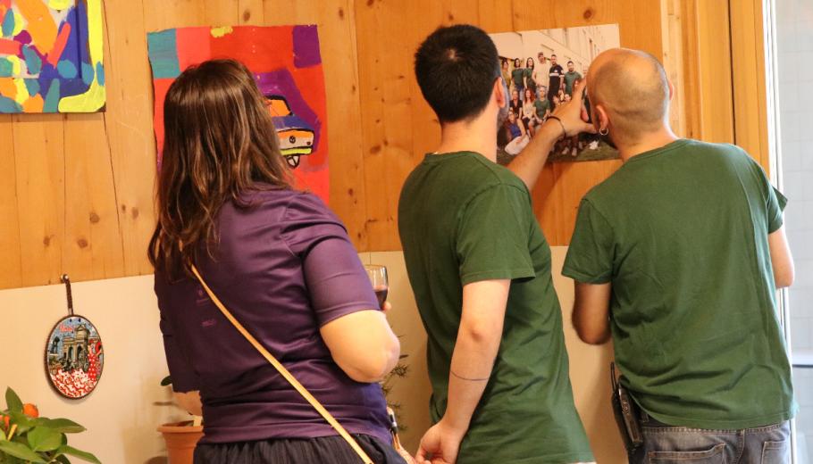 Persones treballadores mirant una de les fotos de l'exposició sorgida arran de la residència artística