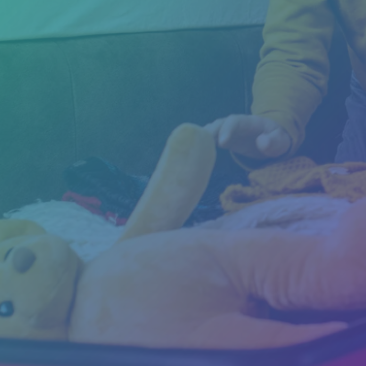 Photo of a child putting a yellow teddy bear in a suitcase