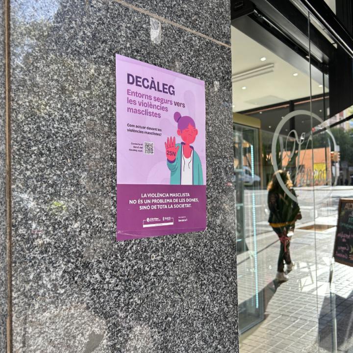 Un cartell de la campanya per difondre el "Decàleg: entorns segurs contra la violència masclista" llueix a l'entrada d'un establiment comercial