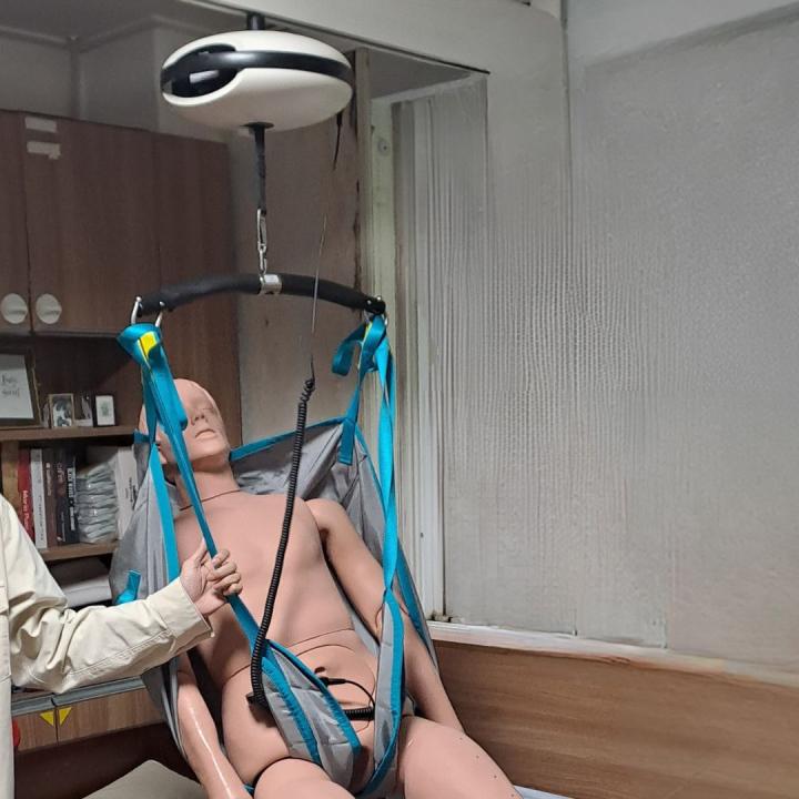 A Korean person showing a robot designed to lift a person in a bed.