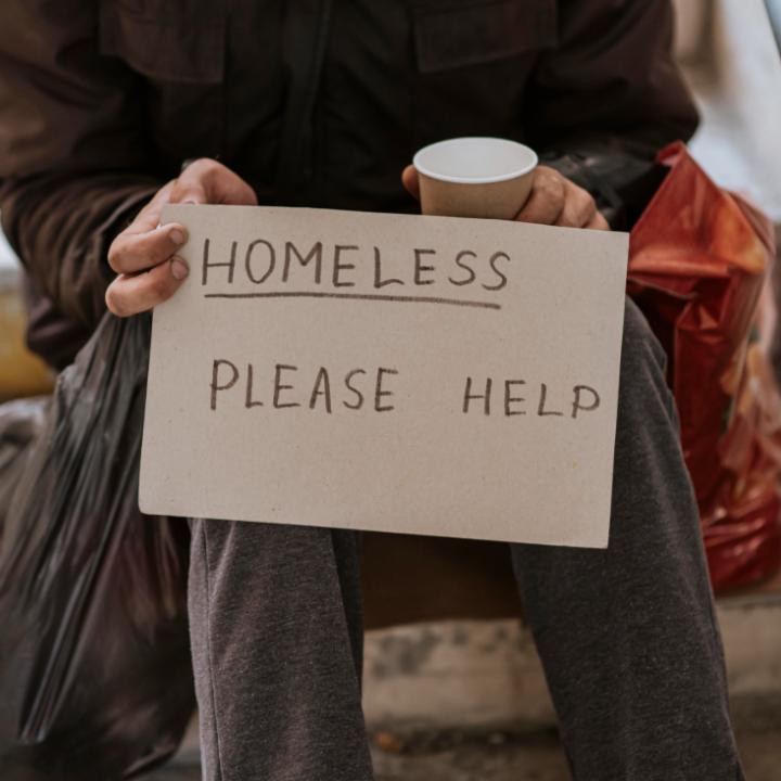 Un home aguanta un cartell. en el qual demana ajuda, perquè viu al carrer 