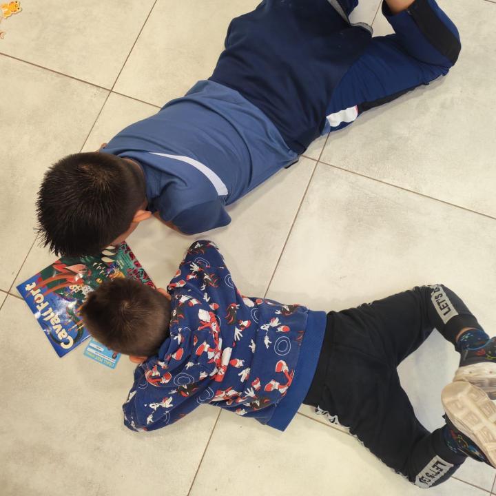 Dos nens del CA de Terres de l'Ebre estan estirats junts a terra llegint Cavall Fort