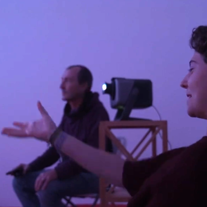 una noia senyalant a la mà i explicant la seva experiència al seu terapeuta en una sala de realitat immersiva