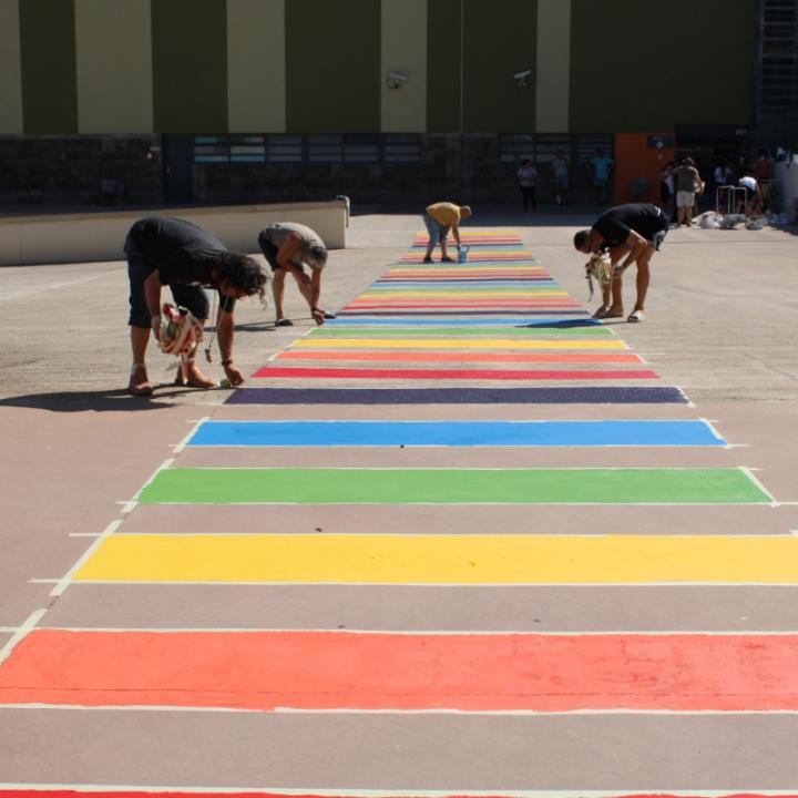 Un grup de persones pinten el pas de zebra amb els colors de la bandera LGTBIQ+
