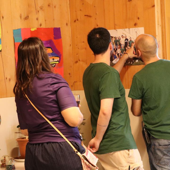 Persones treballadores mirant una de les fotos de l'exposició sorgida arran de la residència artística