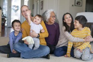 dos adults en actitud d'estima amb quatre infants que somriuren