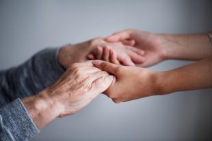Unes mans de dona jova agafen amb cura les mans d'una dona gran