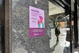 Un cartell de la campanya per difondre el "Decàleg: entorns segurs contra la violència masclista" llueix a l'entrada d'un establiment comercial