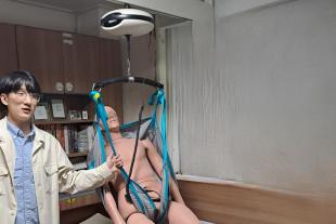 A Korean person showing a robot designed to lift a person in a bed.