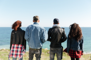 Young people standing with their backs to the sea