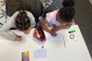 dues nenes fent deures a un servei de reforç escolar