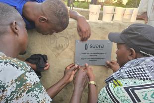 Tres homes pengen la placa de Suara Cooperativa en el pou que s'ha construït al Senegal