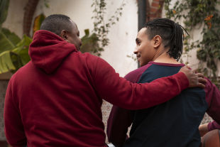 Un home agafa per l'esquena per donar suport un jove, que agafa una pilota de bàsquet