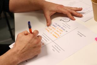 Persona participando en la jornada de cocreación de Suara y DDS escribiendo relatos sobre el valor de las curas.