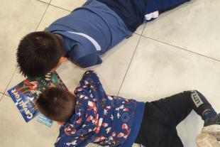 Dos nens del CA de Terres de l'Ebre estan estirats junts a terra llegint Cavall Fort