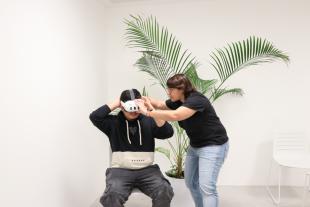 La responsable de realitat virtual, Natalia Alonso, posa les ulleres a un jove per treballar una experiència de realitat virtual