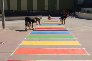 Un grup de persones pinten el pas de zebra amb els colors de la bandera LGTBIQ+