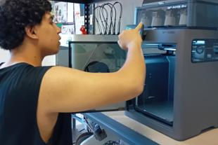 Un jove posa en funcionament una impressora 3D
